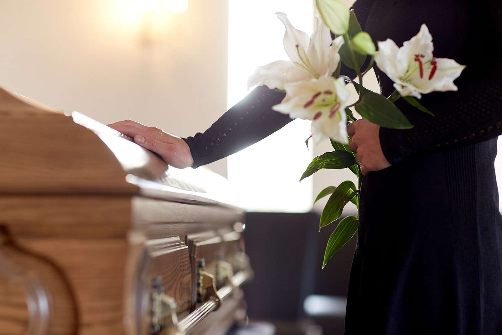 people and mourning concept – woman with white lily flowers and